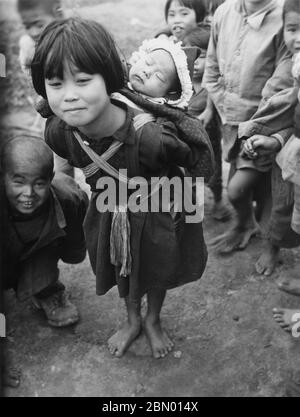 [ 1946 Japan - Okinawan Mädchen trägt Schwester ] - Okinawan Mädchen trägt ihre kleine Schwester in Sokei (惣慶) in dem Dorf Ginoza (宜野座村), Okinawa, 1946 (Showa 21). Silberdruck mit Gelatine aus dem 20. Jahrhundert. Stockfoto