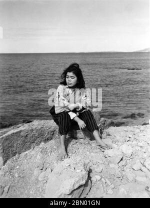 [ 1946 Japan - Okinawan-Frau ] - Junge Okinawan-Frau in einer Hose auf einem Felsen in Taira (田井等) in Nago (名護), Okinawa, 1946 (Showa 21). Silberdruck mit Gelatine aus dem 20. Jahrhundert. Stockfoto