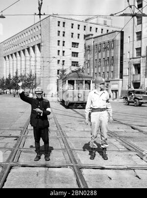 [ 1940er Japan - Besetzung Japans im Zweiten Weltkrieg ] - EIN japanischer Polizeibeamter und ein US-ArmeeMP leiten den Verkehr in der Nähe des Dai-Ichi Seimei-Gebäudes (im Hintergrund zu sehen) in Yurakucho (有楽町), Chiyoda (千代田区), Tokio, ca. 1945 (Showa 20). Das Dai-Ichi Seimei-Gebäude diente als Sitz des Obersten Befehlshabers der Alliierten Mächte (SCAP), der Titel, den General Douglas MacArthur (1880–1964) während der alliierten Besetzung Japans (1945–1951) nach dem Zweiten Weltkrieg hielt Silberdruck mit Gelatine aus dem 20. Jahrhundert. Stockfoto