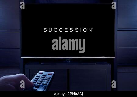 Ein Mann zeigt eine Fernbedienung auf den Fernseher, der den Hauptbildschirm der Nachfolge anzeigt (nur redaktionelle Verwendung). Stockfoto