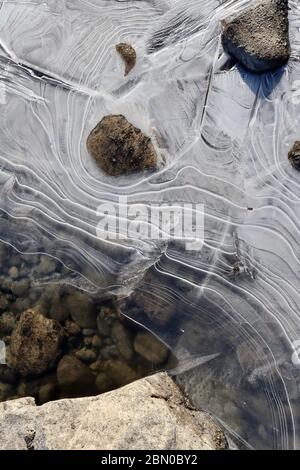 Nahaufnahme von offenen Wasser- und Eisformationen mit eleganten Linien und Flussfelsen während des Frühlings schmelzen entlang des Yukon River. Die Natur ist kreatives Chaos und Stockfoto