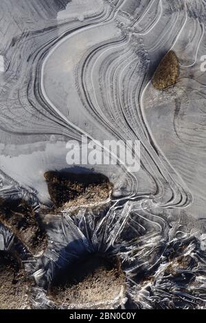 Nahaufnahme von Eisformationen mit eleganten Linien und Flussgestein während des Frühlings schmelzen entlang des Yukon River. Das kreative Chaos der Natur und die zufällige Eleganz Stockfoto