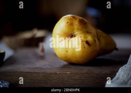 Eine leuchtend gelbe Birne auf einem hölzernen Hintergrund. Stockfoto