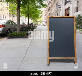 Leere Bürgersteig Tafel oder Tafel Schild auf einer malerischen Baum gesäumten Stadtstraße mit geparkten Autos und Vorkriegswohnungen Gebäude Stockfoto