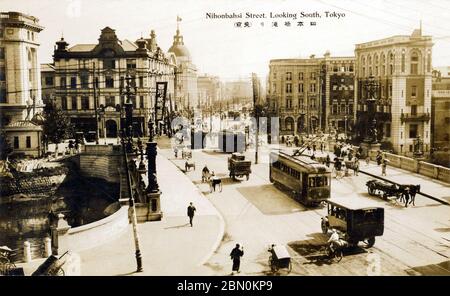 [ 1920er Jahre Japan - Nihonbashi Bridge, Tokyo ] - Straßenbahnen und andere Verkehr überqueren die Nihonbashi Bridge in Tokio. Der Fotograf zeigte seine Kamera nach Süden. Während der Edo-Periode (1600-1867) war die Nihonbashi-Brücke der Ausgangspunkt des berühmten Tokaido und der anderen 4 Poststraßen. Die Steinbrücke mit Bronzelöwen und schmiedeeisernen Gaslampen auf diesem Bild ersetzte die hölzerne im Jahre 1911 (Meiji 44). Vintage-Postkarte des 20. Jahrhunderts. Stockfoto