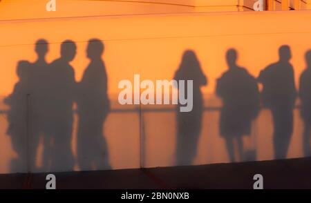 Besucher werfen Schatten auf die Wand des Griffith Park Observatory bei Sonnenuntergang während sie die Skyline von Los Angeles, Kalifornien, USA, sehen Stockfoto