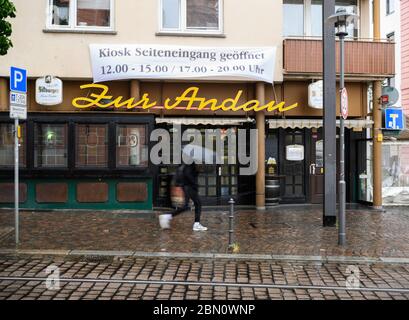 Mainz, Deutschland. Mai 2020. Ein Mann geht mit einem Regenschirm an der traditionellen Kneipe 'zur Andau' vorbei. Die Taverne im Stadtzentrum will unter Einhaltung der Corona Hygienevorschriften wieder eröffnet werden. Die Landesregierung in Rheinland-Pfalz hat zum 13. Mai grünes Licht für das Restaurant gegeben. Quelle: Andreas Arnold/dpa/Alamy Live News Stockfoto