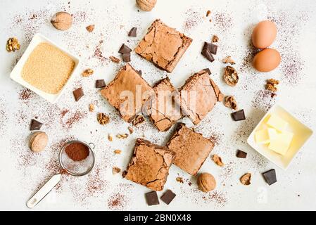 Draufsicht der frisch gebackenen hausgemachten Brownie Kuchen mit Rezeptur Zutaten auf weißem rustikalen Hintergrund angeordnet. Stockfoto
