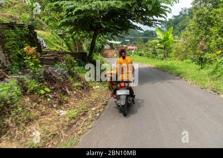 Balinesinnen, die auf einem Roller in Rural Village in Indonesien reiten Stockfoto