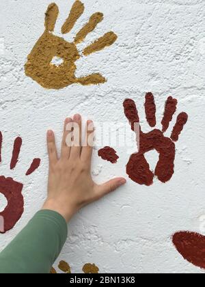 Handdrucke an einer weißen Wand. Zeichnung in heller Tinte, Handdrucke. Hand des Mädchens in der Nähe. Keine Flächen Stockfoto