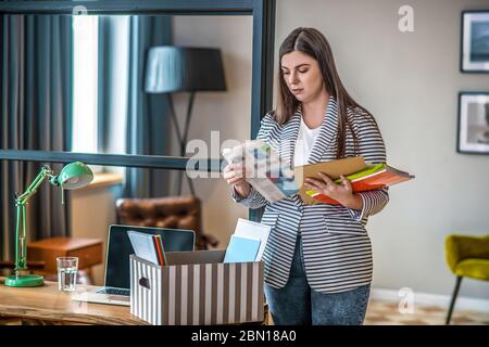 Junge Frau in einer gestreiften Jacke, die eine Zeitung liest Stockfoto