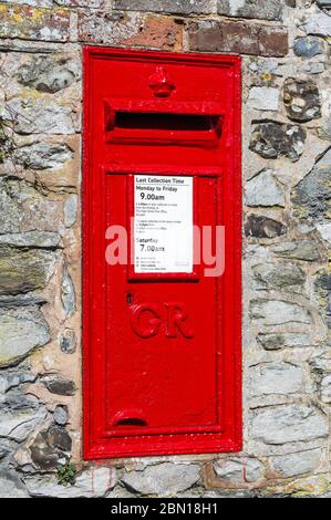 W. T. Allen & Co King George V rechteckige rote britische Wanddose oder Royal Mail Postbox aus dem 19. Jahrhundert, in eine alte Backsteinwand in England, Großbritannien gesetzt. Stockfoto