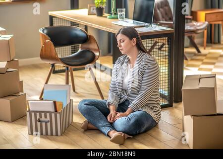 Junge Frau auf dem Boden sitzend und frustriert aussblickend Stockfoto