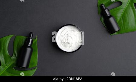 Naturkosmetik Set mit Glas Creme Feuchtigkeitscreme und schwarzen aromatischen Ölflaschen auf schwarzem Hintergrund. Luxus SPA Bio-Beauty-Produkte, Hautpflege, Stockfoto