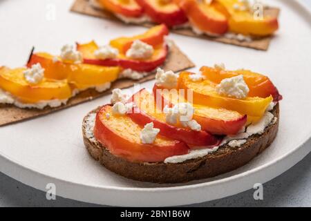 Hausgemachte Sandwiches mit Aprikosen und Ricotta-Käse auf Brot und Crouton auf einem weißen Teller Stockfoto