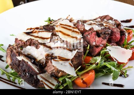 Traditionelles italienisches Hauptgericht. Rindfleisch Tagliata: Zartes Rindsrippenauge, Rucola, Kirschtomaten, Grana Padano Späne, Balsamico Reduktion. Emilia Romagna Stockfoto