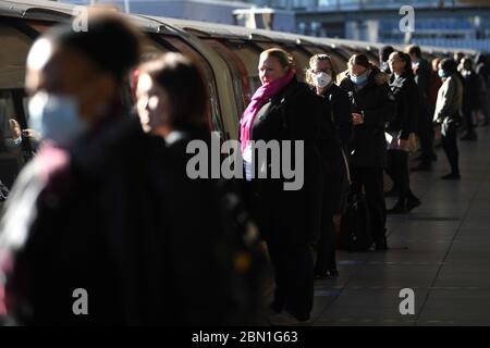 Pendler warten, um einen Zug in Canning Town U-Bahn-Station in London, nach der Ankündigung der Pläne, das Land aus der Sperrung zu bringen. Stockfoto