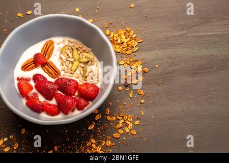 Gericht mit Joghurt, Erdbeeren, Müsli, Nüssen, ideal für eine energiegeladene vegetarische Ernährung Stockfoto