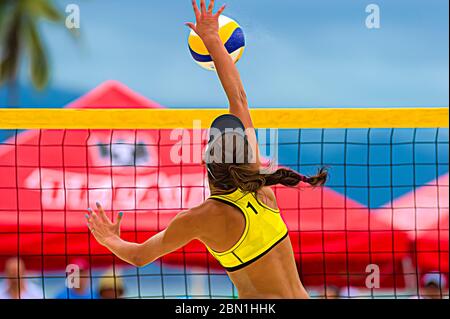 Eine Volleyballspielerin erhebt sich am Netz, um den Ball nach unten zu spike Stockfoto