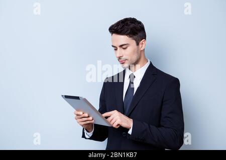 Fokussierte gut aussehende junge Brunete Börse Broker ist auf seiner Tablette tippen, in einem formalen tragen auf dem reinen Hintergrund stehen. So ernst und Stockfoto