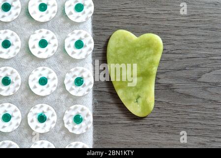 Gua Sha Werkzeug aus Naturstein aus grüner Jade mit Akupressur Matte. Alternative Medizin und Selbstmassage zu Hause Massage Konzept. Selektiver Fokus Stockfoto