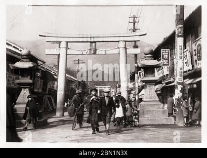 [ 1930er Jahre Japan - Sacred Torii Gate in Shopping Street in Kobe ] - Steinlaternen und ein verängstigter Torii-Tor am Eingang zum Ikuta Jinja, einem schintoistischen Schrein in Kobe, Präfektur Hyogo, Ca 1932 (Showa 7). Viele Geschäfte säumen die Straße. Der Schrein gehört zu den ältesten Schreinen in Japan und wird im Nihon Shoki, dem zweitältesten Buch der klassischen japanischen Geschichte, erwähnt. Die Schlacht von Ichi-no-Tani (1184) fand im und um den Ikuta-Schrein statt. Silberdruck mit Gelatine aus dem 20. Jahrhundert. Stockfoto