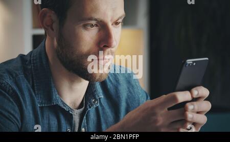 Junger Mann sucht Handy-Bildschirm Stockfoto