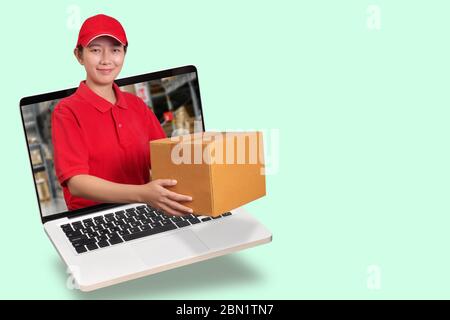 Asiatische Lieferung Frau in rotem Hemd mit Blur Lager Hintergrund, hält Ware Ordnung in Paket Paket aus Laptop-Computer isoliert Stockfoto