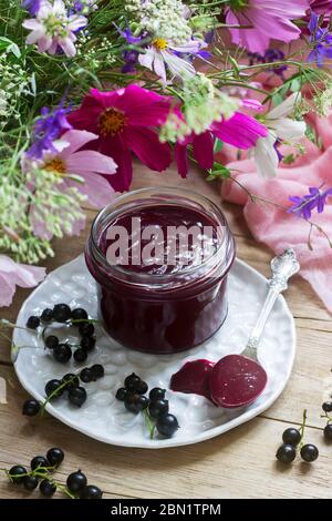 Schwarze Johannisbeere Custard, Korinthen und einen Strauß Blumen auf einem hölzernen Hintergrund. Im rustikalen Stil. Stockfoto