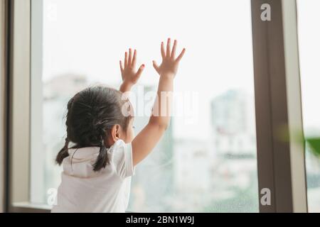 Rückansicht auf niedlichen kleinen Mädchen schaut aus dem Fenster Stockfoto