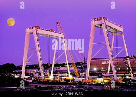 Massive Krane zum Heben von Windenergieanlagen-Teilen im Mondlicht Stockfoto