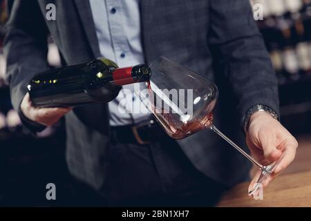 Sommelier Mann gießt Rotwein in Glas ohne zu spritzen Stockfoto