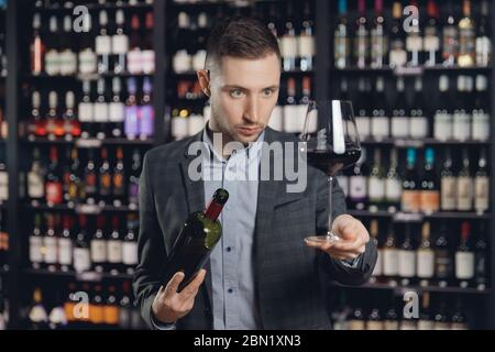 Der Sommelier gießt Rotwein aus der Flasche in den Glaspelz im Restaurant Stockfoto