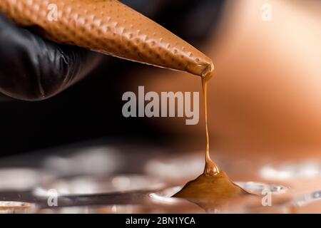 Koch oder Chocolatier gießt geschmolzene dunkle Schokolade in Silikonformen auf den Gebäckbeutel Stockfoto