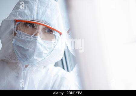 Müde Blick Arzt Frau Biohazard Blick aus dem Fenster, schlaflose Nächte arbeiten in Quarantäne Coronavirus Krankenhaus Stockfoto