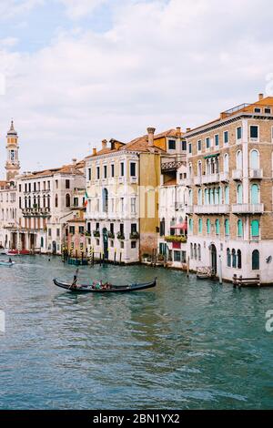 Eine Gondel mit Touristen segelt entlang des Canale Grande inmitten der Fassaden venezianischer Häuser, die in Venedig, Italien, auf dem Wasser stehen. Stockfoto