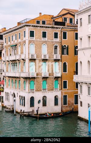 Venedig, Italien - 04. oktober 2019: Eine Gondel mit Touristen fährt entlang des Canale Grande inmitten der Fassaden venezianischer Häuser, die auf dem Wasser stehen Stockfoto
