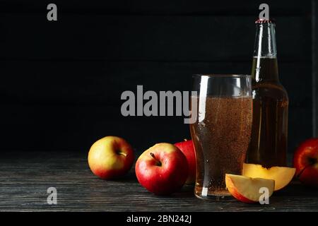 Komposition mit Apfelwein und Äpfeln auf Holzhintergrund Stockfoto