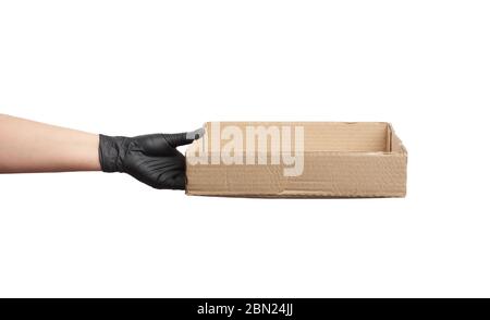 Weibliche Hand in einem schwarzen Latexhandschuh hält eine braune Kartonschachtel auf weißem Hintergrund, sichere und kontaktlose Lieferung von Online-Bestellungen bei Epidemien Stockfoto