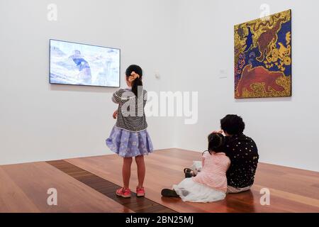 Mutter und zwei Kinder, die sich Kunstwerke in der National Gallery of Victoria, Aboriginal Galleries, Melbourne, Victoria, Australien ansehen Stockfoto