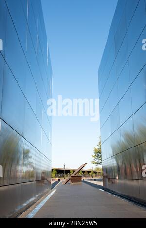 Vertikale Ansicht des 911 Memorial im Liberty State Park mit einem Stück der Twin Towers im Hintergrund als Denkmal. Stockfoto