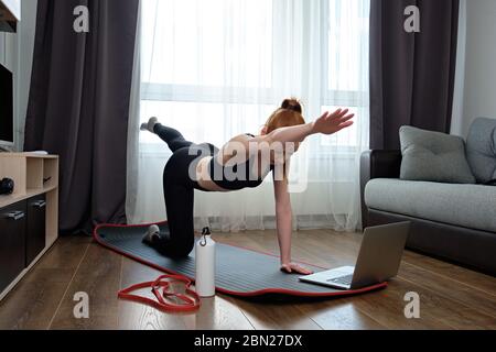 Redhead schlanke Mädchen in Sportuniform ist im Sport vor einem Laptop engagiert. Stockfoto