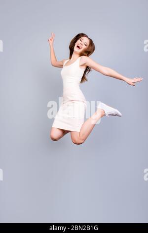 Glück, Traum, Spaß, Freude Konzept. Sehr aufgeregt glücklich Mädchen springt auf einem hellen Hintergrund, tragen Casual weißen Outfit und Schuhe, gesturing V Stockfoto