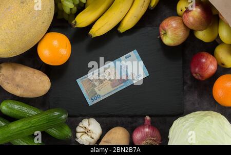 Kartoffel Kohl Banane Melone Kohl Gurken Zwiebel Knoblauch Orange Äpfel Birne Geld ein dunkler Hintergrund Syrien Geld Stockfoto