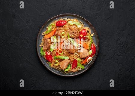 Pad Woon Sen oder Thai Pork Glass Noodle Stir-Fry in schwarzer Platte auf dunklem Schieferhintergrund. Pad Woon Sen ist ein thailändisches Gericht aus Glasbohnennudeln, Fleisch Stockfoto
