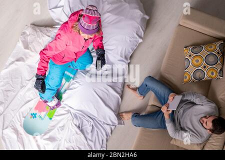 Über Ansicht des jungen Mannes lesen Ratschläge auf Tablet-PC zu Freundin, die lernen, Snowboard in der Isolation zu Hause Stockfoto