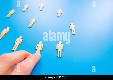 Die gewählte Person unter anderem. Eine menschliche Figur aus Holz hebt sich von der Menge ab. Holzfiguren von Menschen. Ein talentierter Mitarbeiter, eine erfolgreiche Wahl. Stockfoto