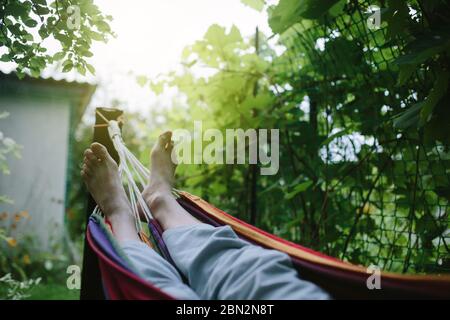 Männliche Füße in Hängematte Nahaufnahme, unkenntliche Person, Sommerruhe und Urlaub am Naturkonzept Stockfoto