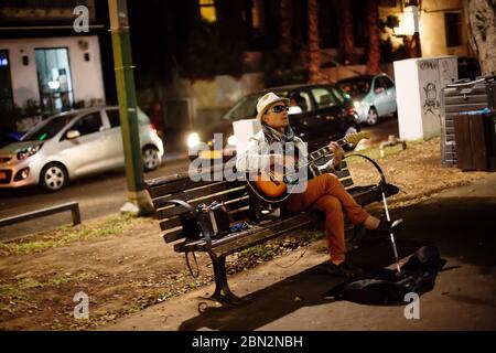 TEL AVIV, ISRAEL - 12. Oktober 2013: Blinder Straßenmusiker und Sänger mit Gitarre sitzt nachts auf einer Bank auf dem Rothschild Boulevard Stockfoto