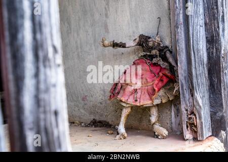 Alte, schmutzige und gesichtslose Puppe, die in einem Fensterrahmen in einem verlassenen Haus in den Bergen von La Gomera, Kanarische Inseln steht. Verflucht, gebrochen und böse g Stockfoto